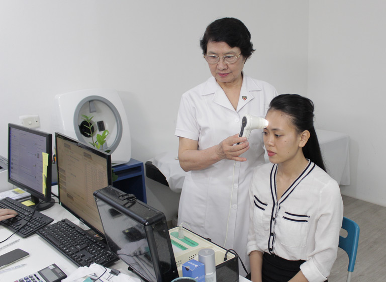Bác sĩ Nhuần soi da và tư vấn cho chị Trang phương pháp trị mụn phù hợp